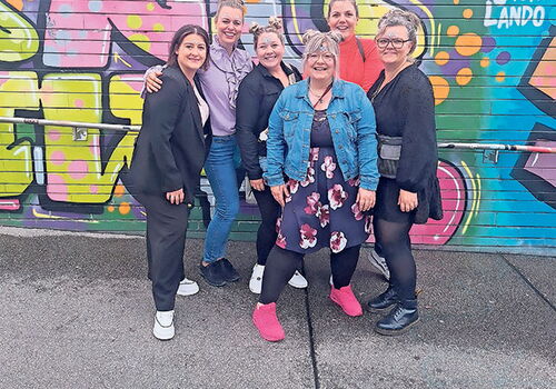 Sechs Frauen vor einer bunten Graffiti-Wand.