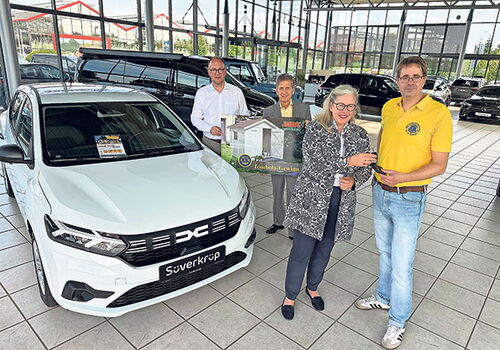 Vier Personen bei der Autoübergabe im Autohaus.
