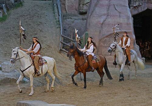 Drei Reiter in Kostümen auf Pferden im Freilichttheater.