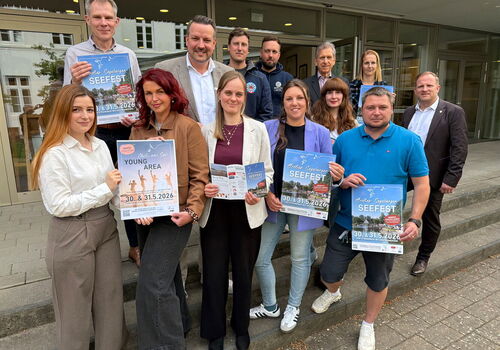 Personen halten Seefest-Poster vor einem Gebäude