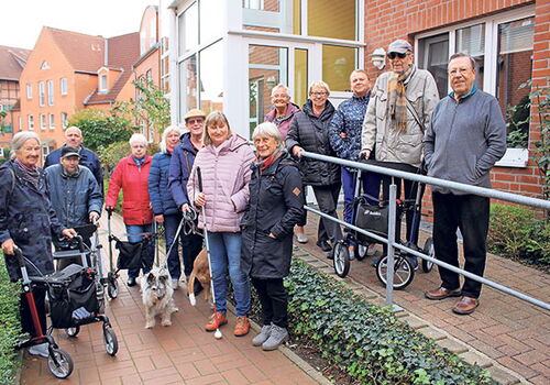 Gruppe von Senioren und Hunden vor einem Gebäude