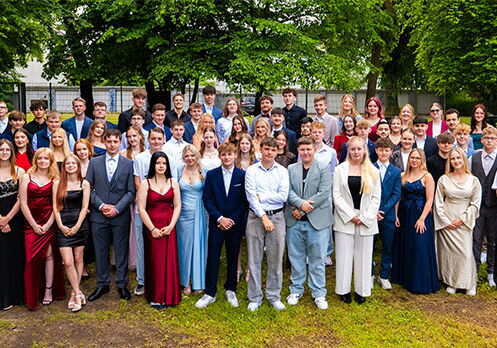 Gruppenfoto von festlich gekleideten jungen Erwachsenen im Freien.