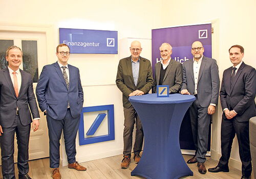 Sechs Männer in Anzügen vor einem Finanzagentur-Schild.