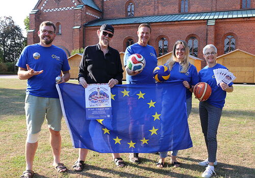 Gruppe vor Kirche mit EU-Flagge und Sportbällen