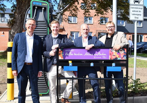 Vier Männer stehen vor einer Ladestation im Freien.