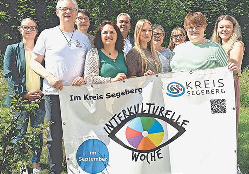 Personengruppe hält Banner für Interkulturelle Woche.