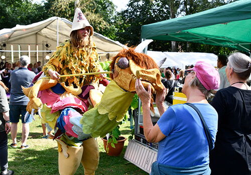 Person in Kostüm auf Stelzen auf einem Festival.