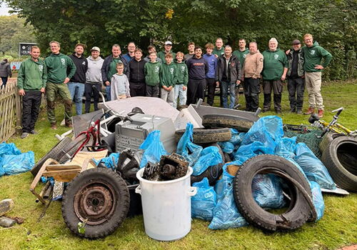Gruppe steht hinter gesammeltem Müll im Park.