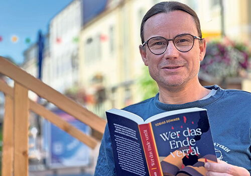Mann liest ein Buch in einem gemütlichen Außenbereich.