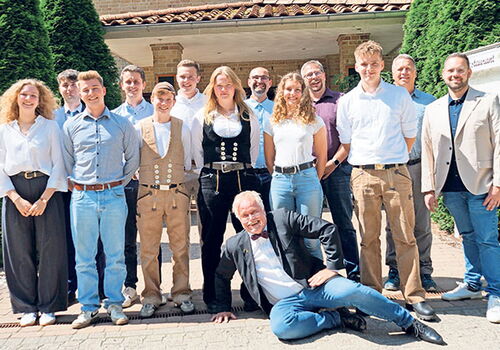 Gruppe von 14 Personen posiert lächelnd am Eingang.