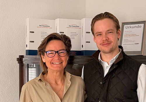 Zwei Personen stehen lächelnd vor einem Regal.