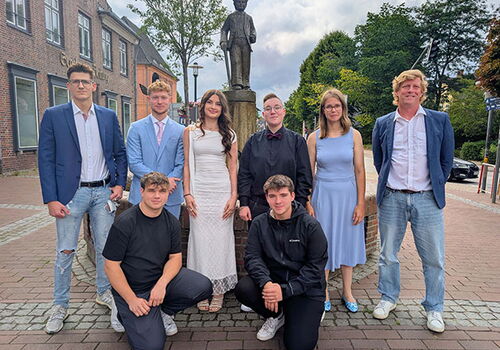 Gruppe von acht Personen vor einer Statue in der Stadt.
