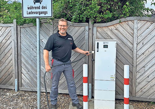 Mann steht neben Ladesäule mit Parkschildern im Hintergrund.