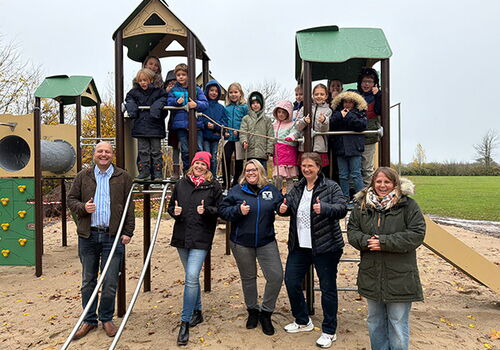 Kinder und Erwachsene posieren auf einem Spielplatz.