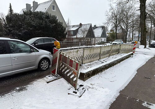 Baustelle auf verschneiter Straße mit parkenden Autos