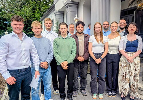 Gruppe von Menschen posiert draußen vor einem Gebäude.