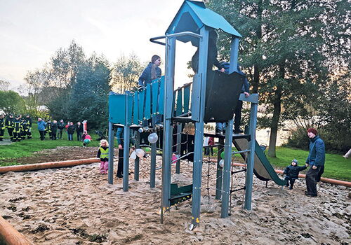 Kinder spielen auf einem hölzernen Klettergerüst im Sand.