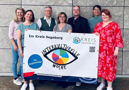 Gruppe posiert mit Banner zur Interkulturellen Woche.