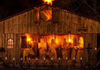 Leuchtende Weihnachtskrippe mit Holzfiguren bei Nacht.