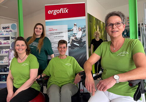 Vier Frauen vor einem ergoflix-Werbeposter in einem Geschäft.