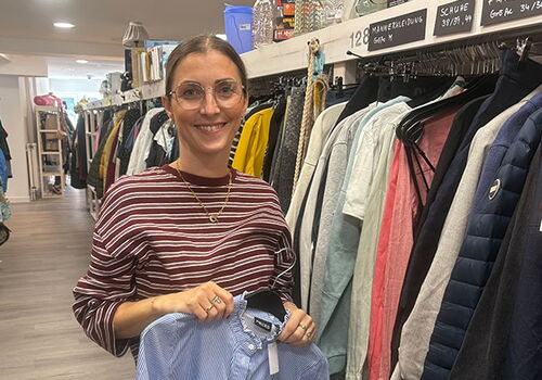 Frau hält Hemd in Secondhand-Laden.
