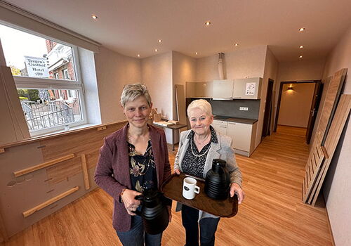 Zwei Frauen mit Tablett im modernen Raum.