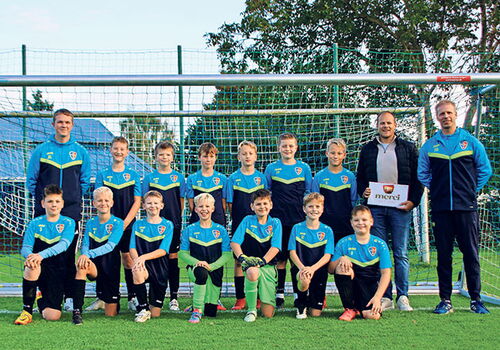 Jugend-Fußballmannschaft vor einem Tor posiert.