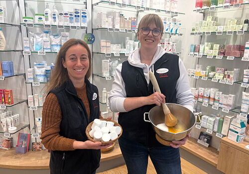 Zwei Frauen mit Schalen in einer Drogerie vor Produkten.