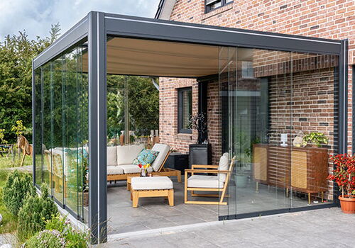 Moderner Wintergarten mit Glaswänden und gemütlicher Einrichtung