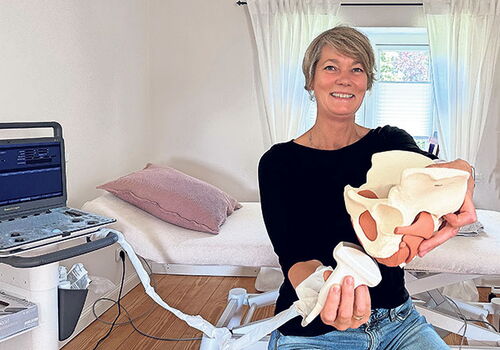 Frau hält ein Modell des Beckens in einer Arztpraxis.