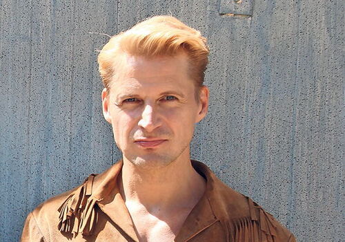 Bastian Semm in brauner Cowboy-Kleidung vor einer Wand.