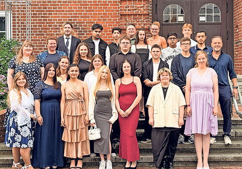 Gruppenfoto von Menschen auf einer Treppe vor einem Gebäude.