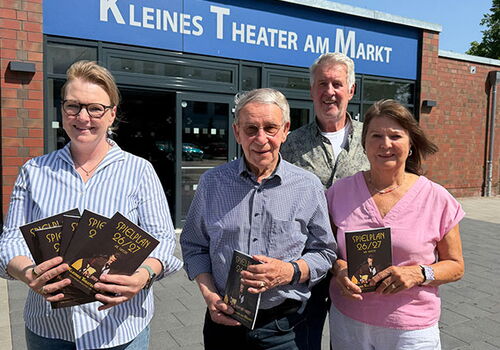 Vier Personen halten Programme vorm Theater.