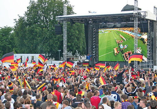 Menschenmenge bei Fußballübertragung mit Deutschlandflaggen