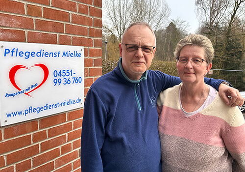 Zwei Personen vor einem Schild des Pflegedienstes Mielke.