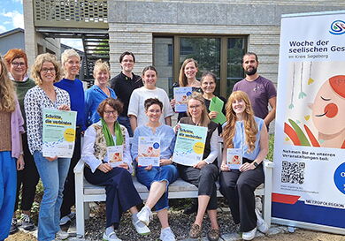 Gruppe von 16 Personen vor Plakat der seelischen Gesundheit.