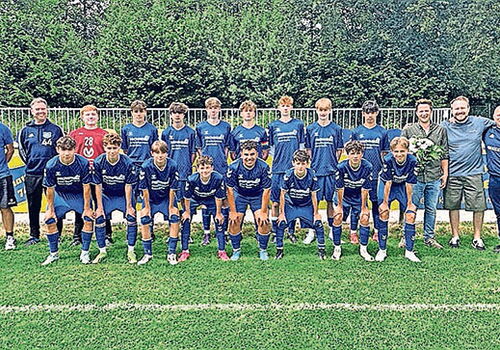 Fußballmannschaft posiert auf einem Spielfeld.