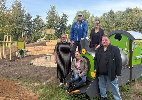 Gruppe von Menschen auf einem Spielplatz mit Holzzug.