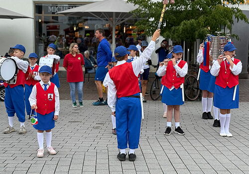 Kinder in Blaskapelle-Uniform proben auf einem Platz.