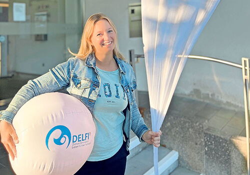 Frau mit Delfi-Ball und Fahne vor einem Gebäude