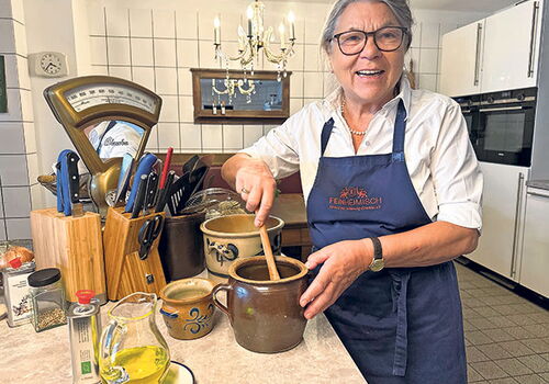 Frau rührt in einem Tontopf in einer gemütlichen Küche