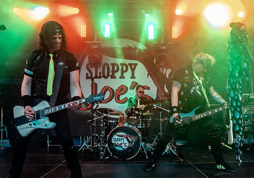 Band spielt Rockmusik auf einer beleuchteten Bühne.