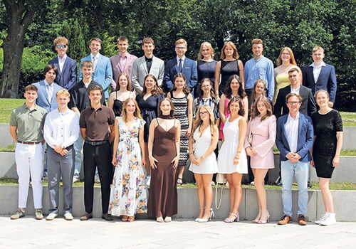 Gruppe von jungen Erwachsenen in formeller Kleidung im Freien.