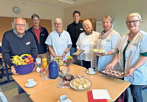 Gruppe von Menschen lächelt in einem Raum mit Snacks.