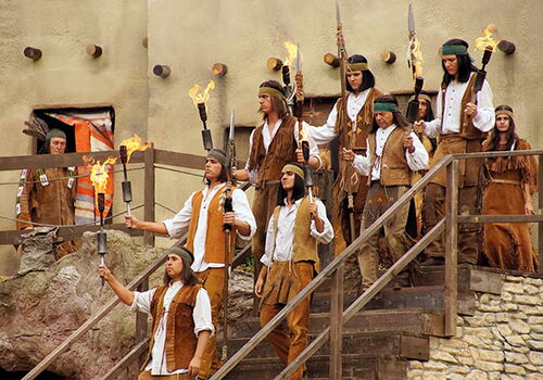Menschen in Kostümen mit Fackeln auf einer Treppe.