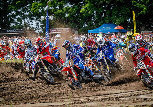 Motocross-Rennen auf sandiger Strecke mit vielen Fahrern.