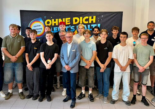 Gruppe von Männern vor einem Banner bei einem Event.