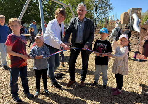 Menschen durchschneiden Band auf Spielplatz-Eröffnung.