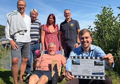 Gruppe von Menschen posiert im Freien bei Sonnenschein.