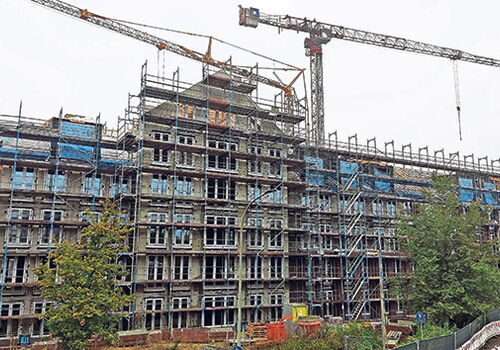 Baustelle mit Gerüst und Kran bei einem Mehrfamilienhaus.
